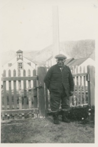 Image of Eskimo [Inuk] man standing near church